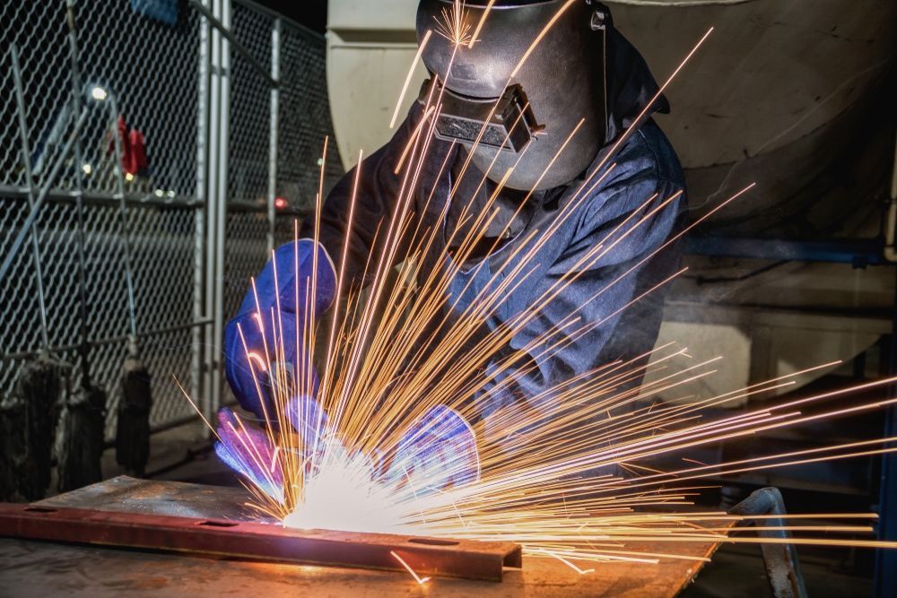 A Man is Welding a Piece of Metal in a Factory — Sun City Sheetmetal In Garbutt, QLD