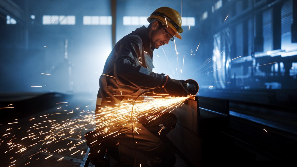 A Man is Grinding a Piece of Metal in a Factory — Sun City Sheetmetal In Garbutt, QLD