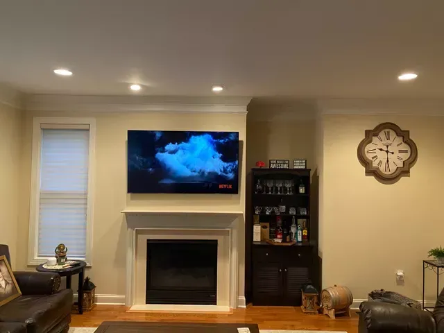 a living room with a fireplace and a newly installed flat screen tv on the wall .