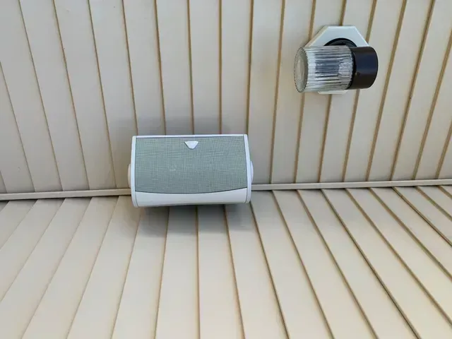 a newly installed jbl speaker is mounted on a wall next to a light for outdoor entertainment