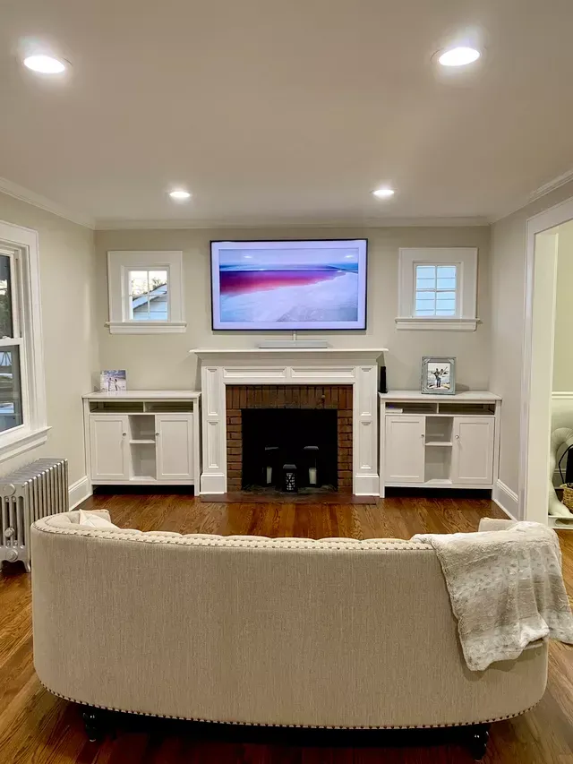 a living room with a couch , fireplace and newly installed television .