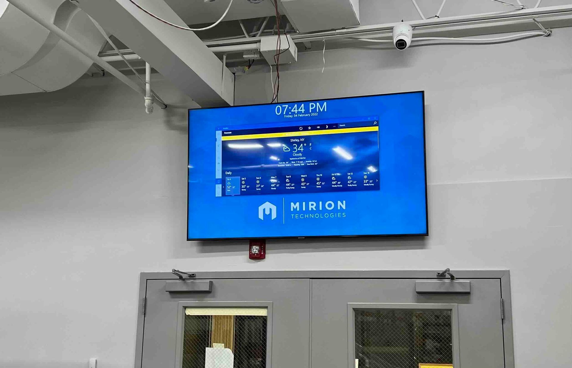 a newly installed large monitor is hanging on a wall above a door in a commercial establishment