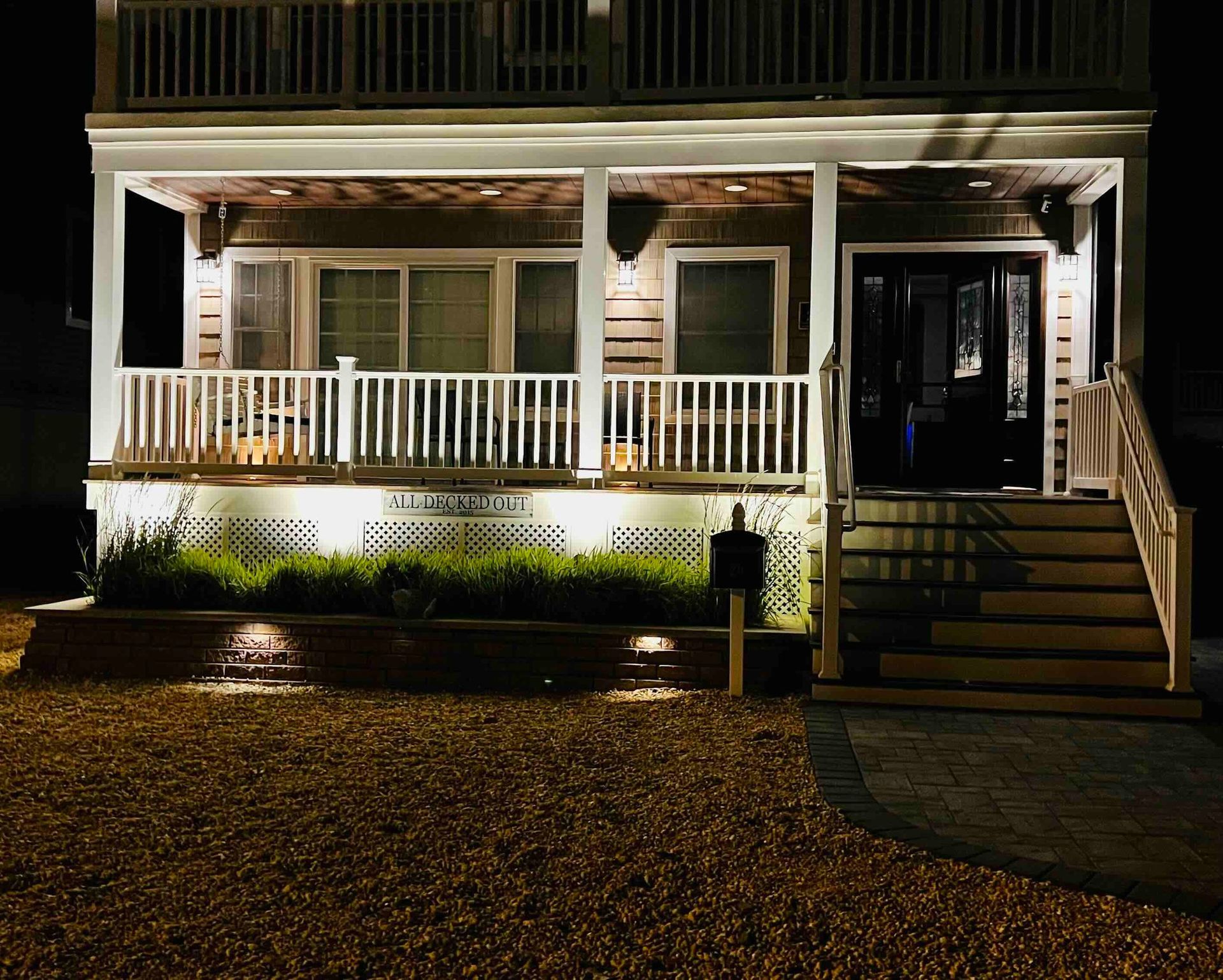 a house with a porch and stairs is lit up at night .