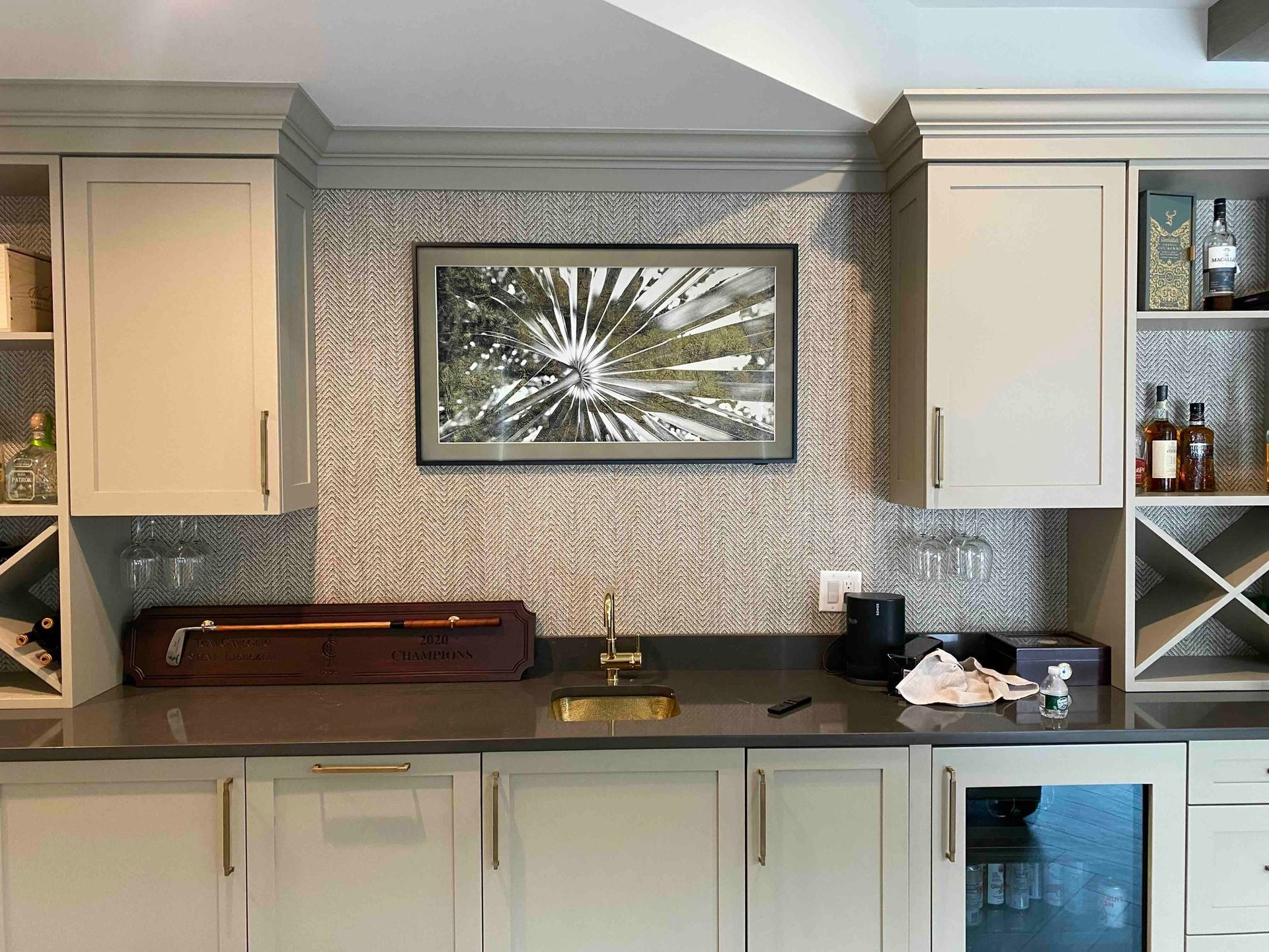 a kitchen with white cabinets , a sink , a refrigerator , and a picture on the wall above the sink .