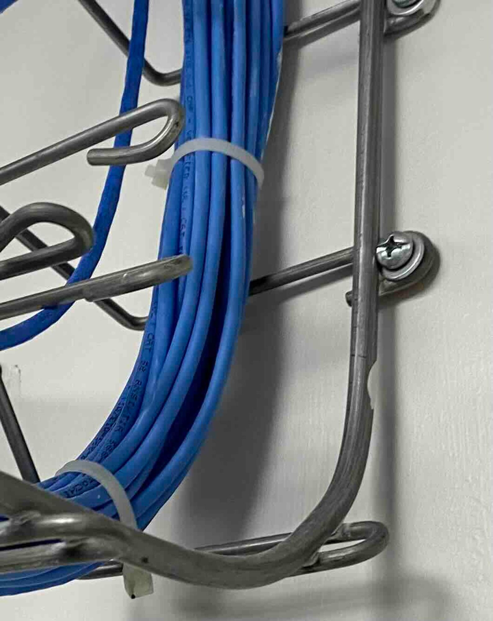a bunch of blue wires are hanging on a wire rack for networking