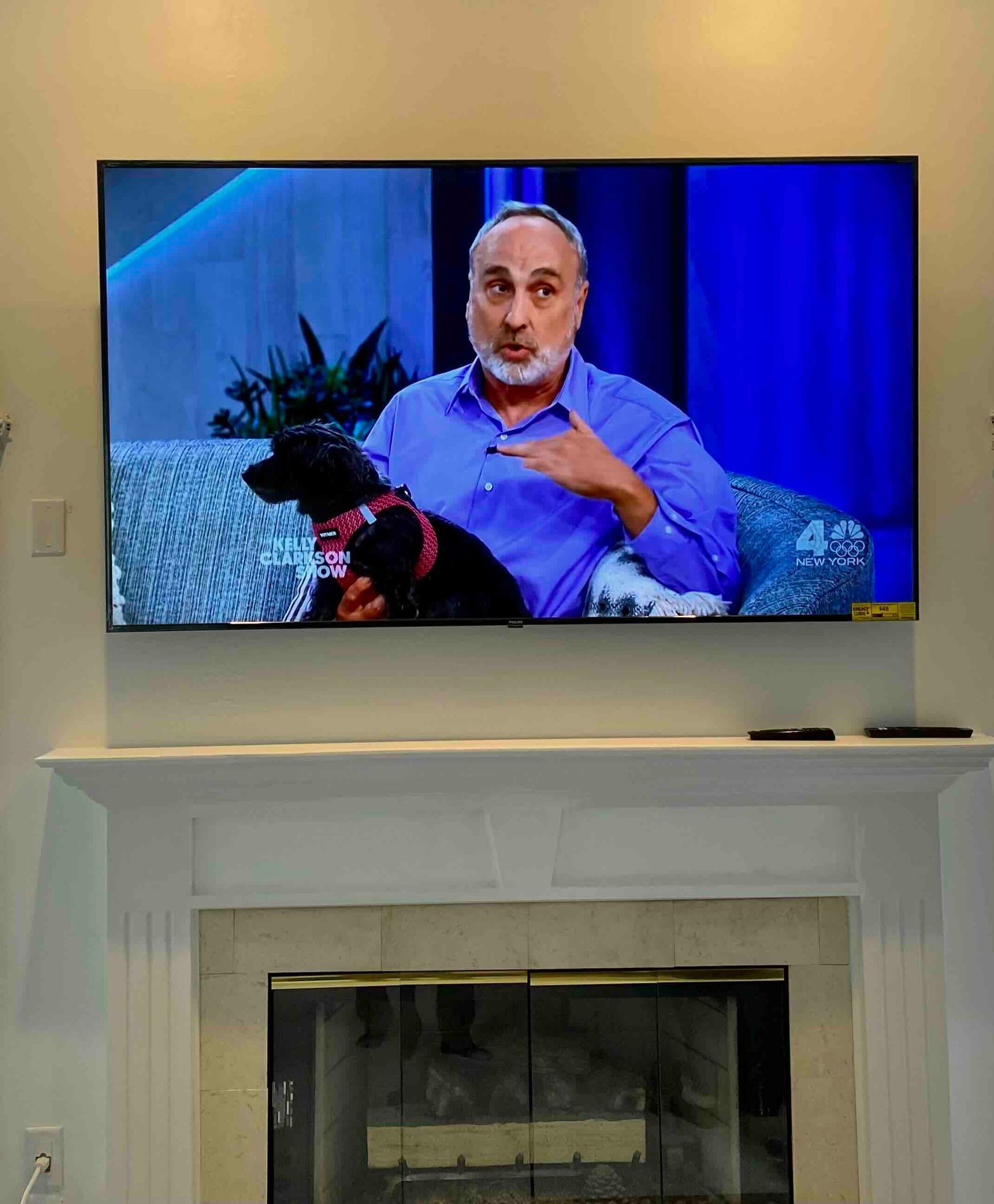 a newly installed flat screen tv is hanging on a wall above a fireplace .