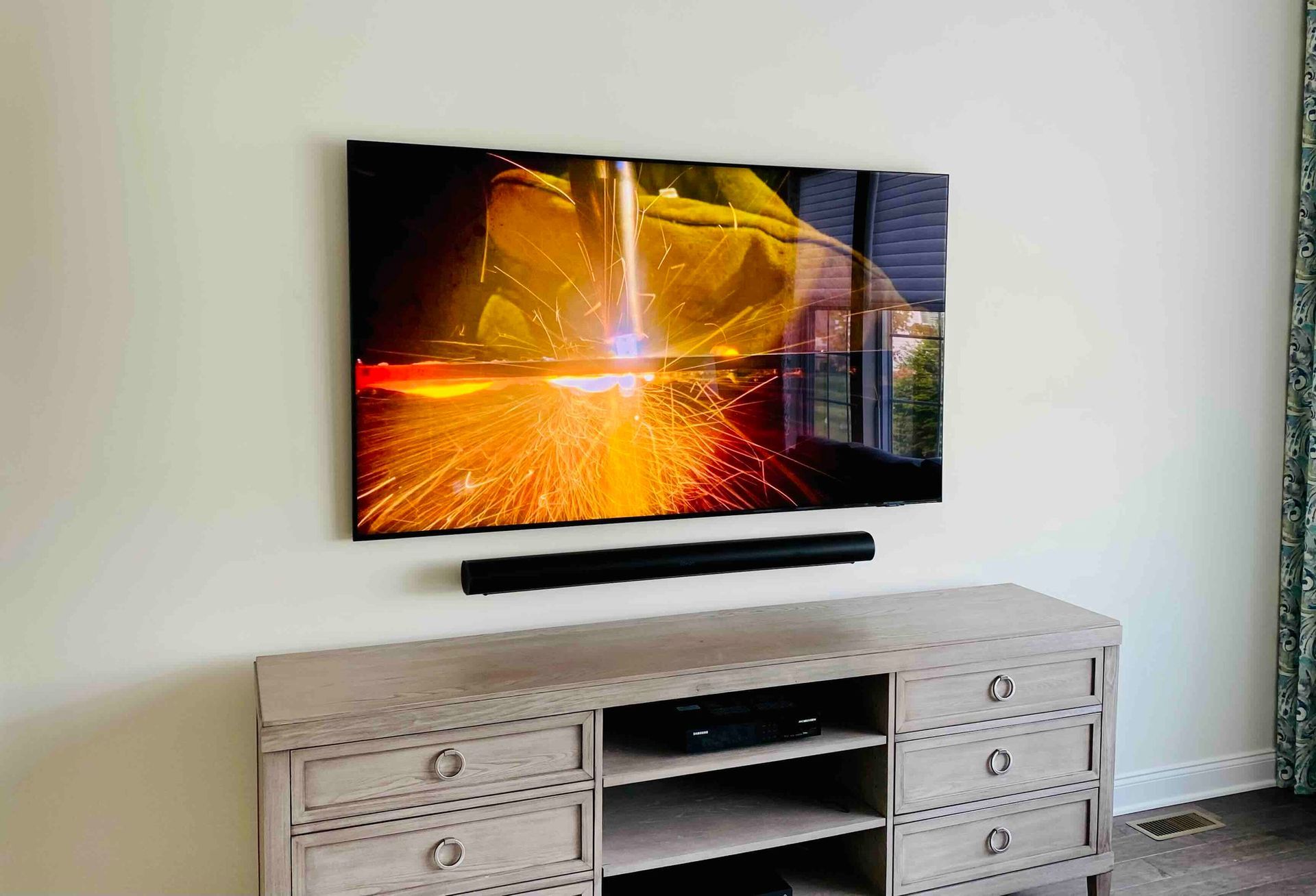 a newly installed flat screen tv is mounted on a wall above a wooden entertainment center .