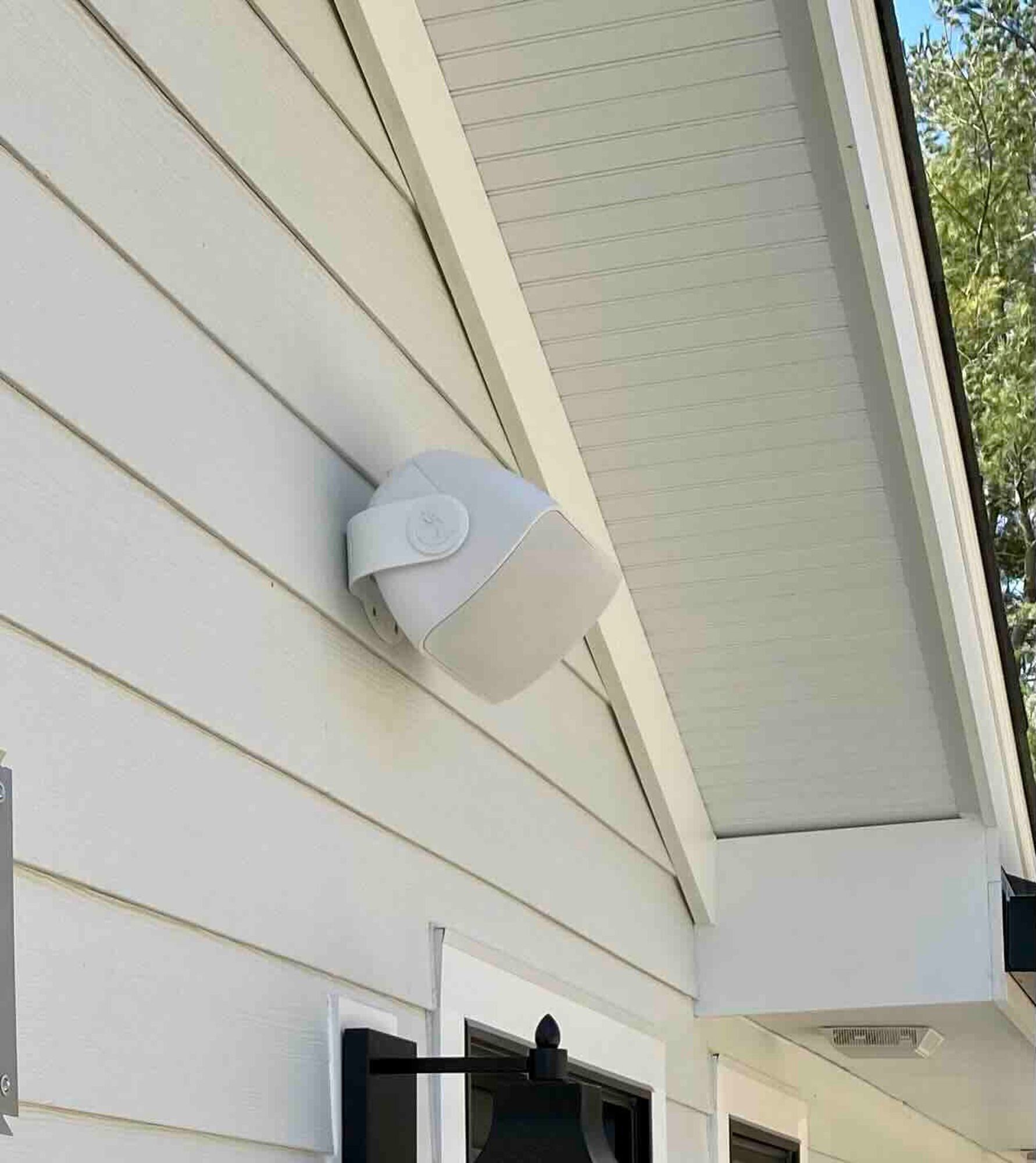 a newly installed white speaker is mounted on the side of a house .