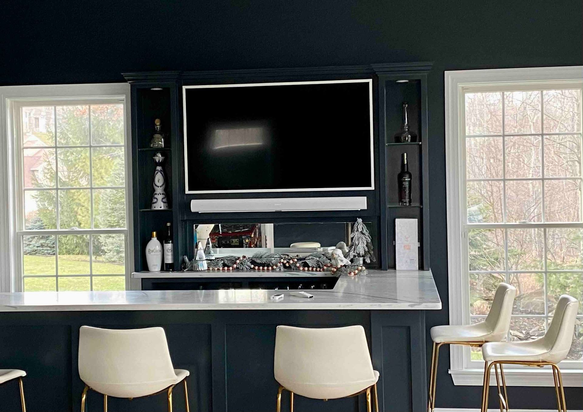 a kitchen with a bar , chairs and a newly installed flat screen tv .