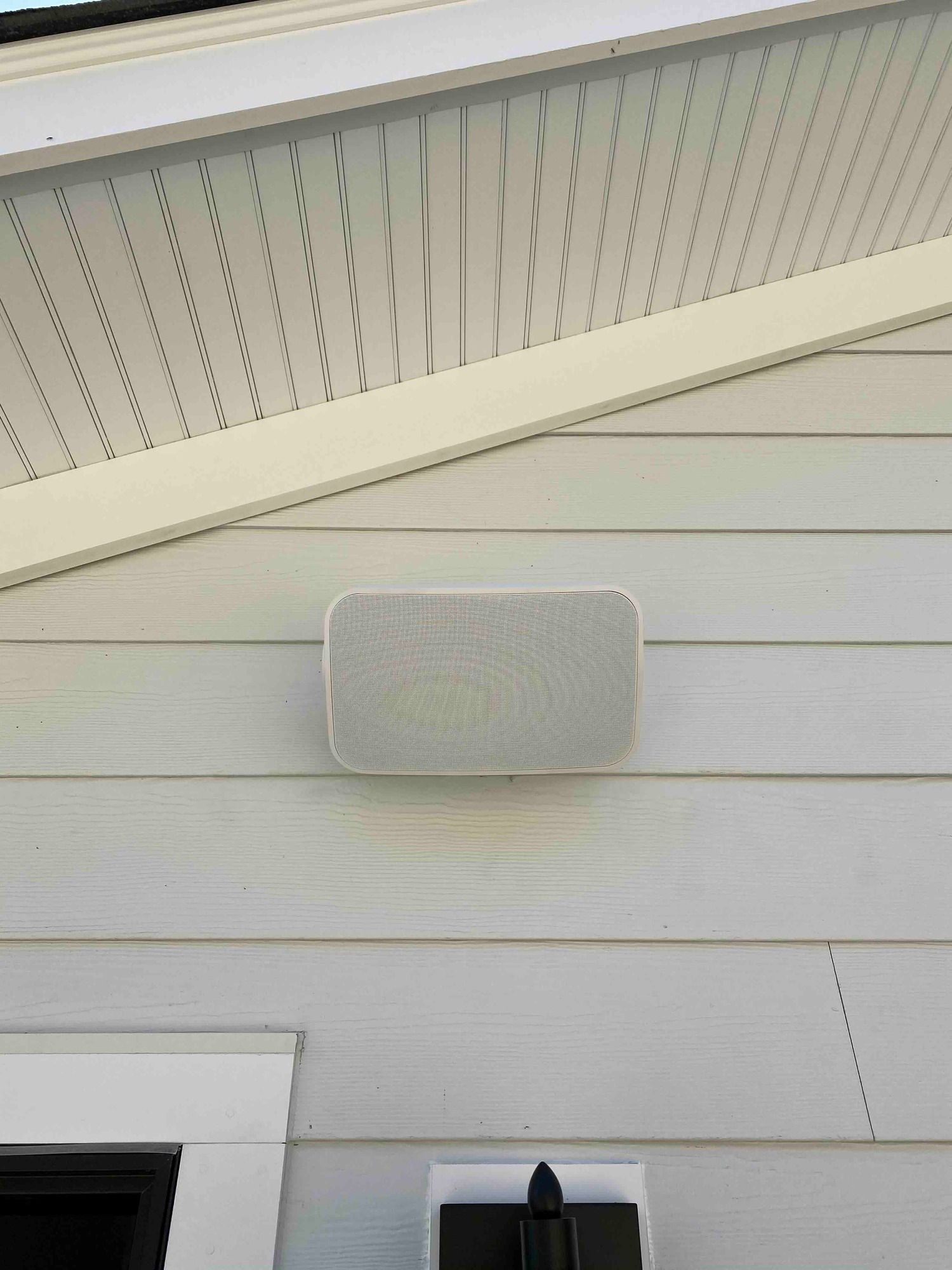a newly installed speaker is mounted on the side of a house for the outdoor entertainment