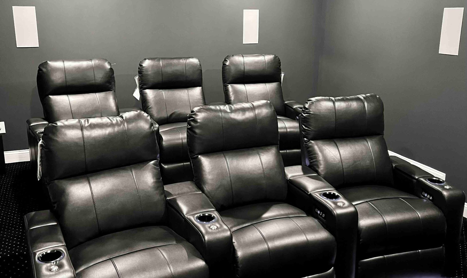 a row of black leather chairs in a home theater