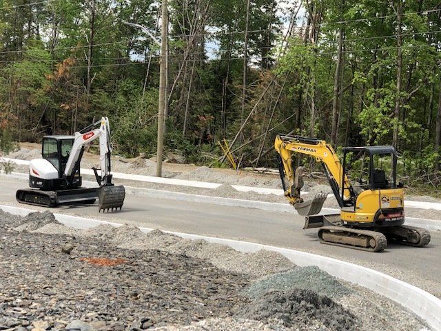 Deux excavatrices roulent l’une à côté de l’autre sur une route.