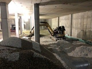 Un chantier de construction avec un tas de gravier et une excavatrice.