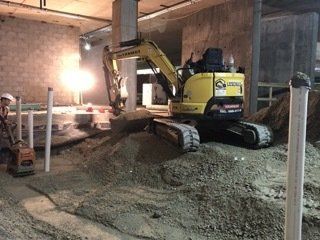 Une excavatrice jaune creuse un trou dans un chantier de construction.