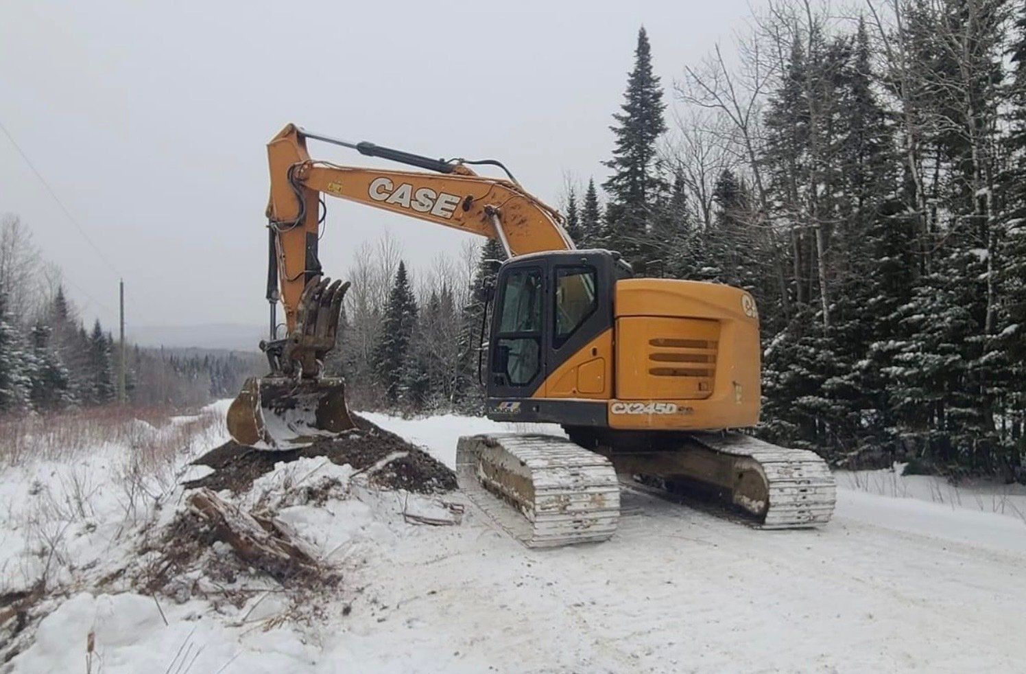 Une excavatrice est garée sur le bord d'une route enneigée.