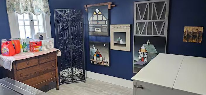 Blue-walled room with holiday decor, a dresser, decorative shelves, and a white table in the foreground