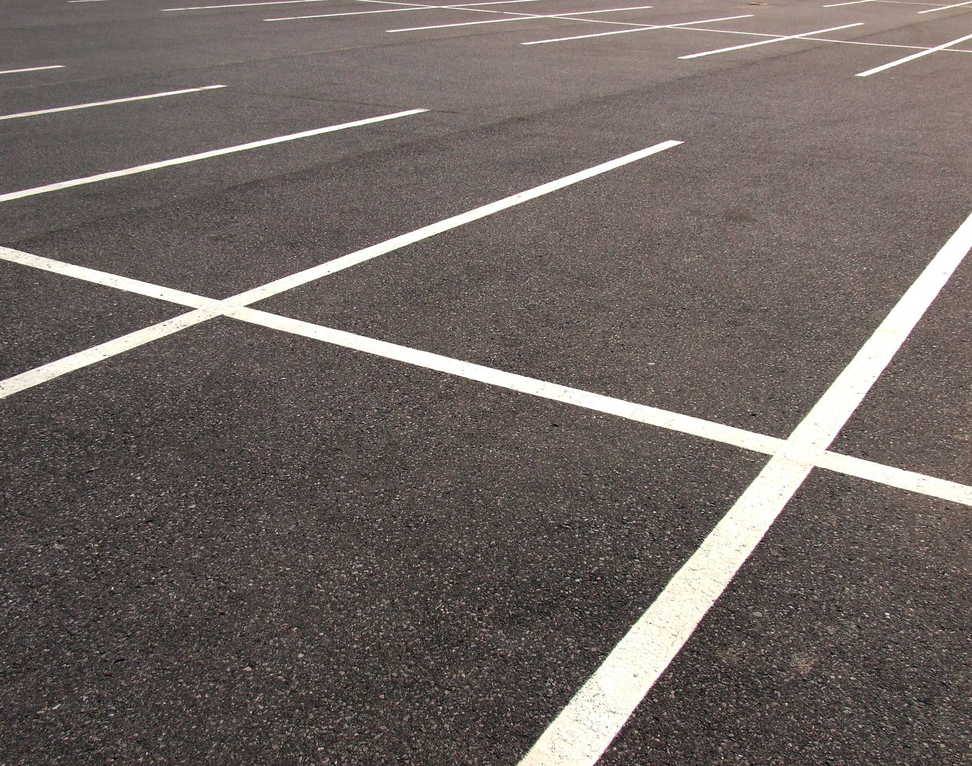 Empty parking lot with white painted lines on dark pavement