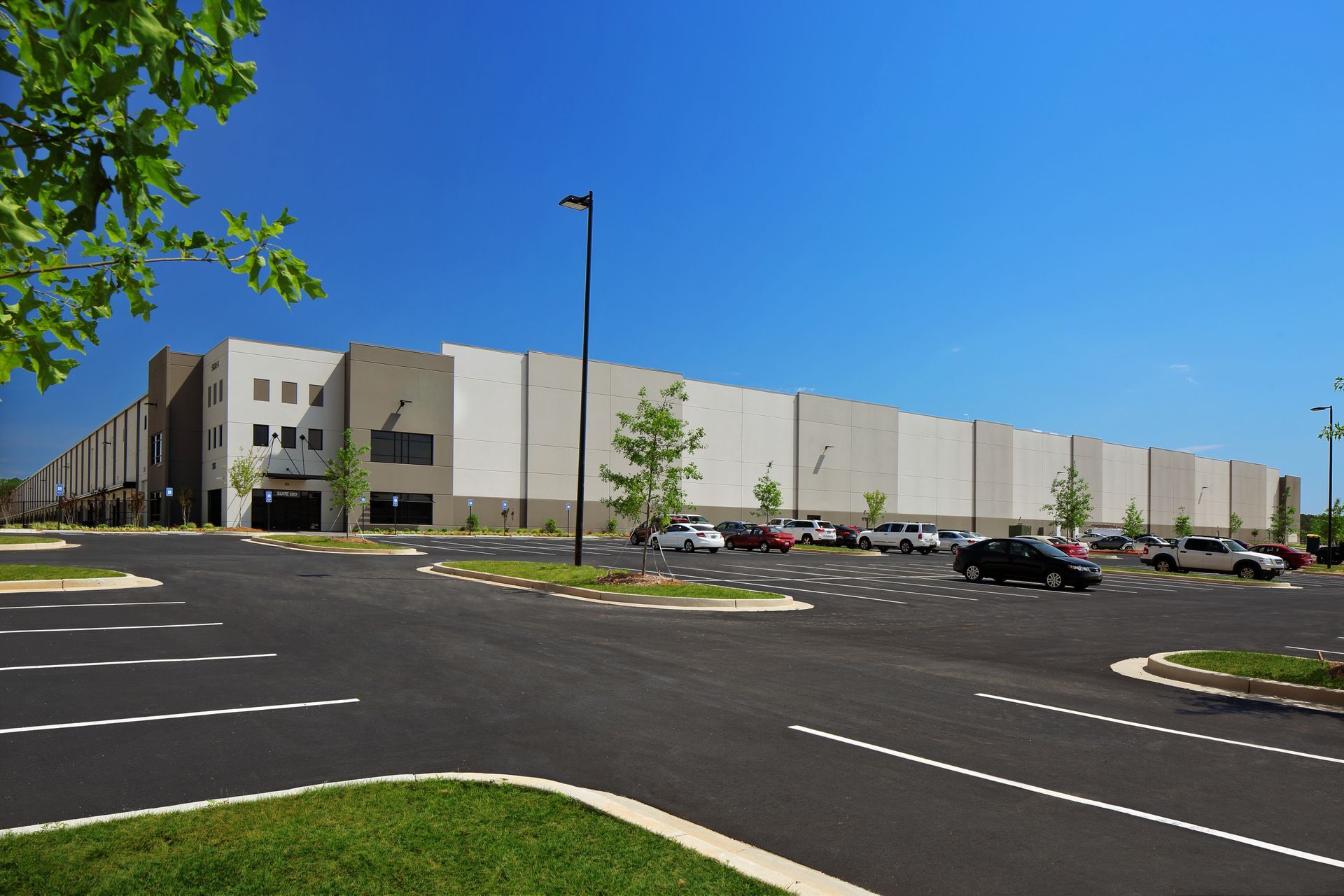Large industrial warehouse building with parking lot and clear blue sky. Large industrial warehouse building with parking lot and clear blue sky.