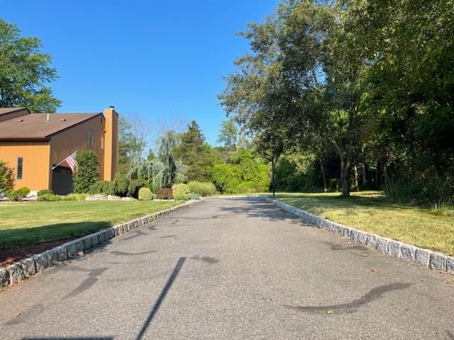 A driveway leading to a house with a white fence.