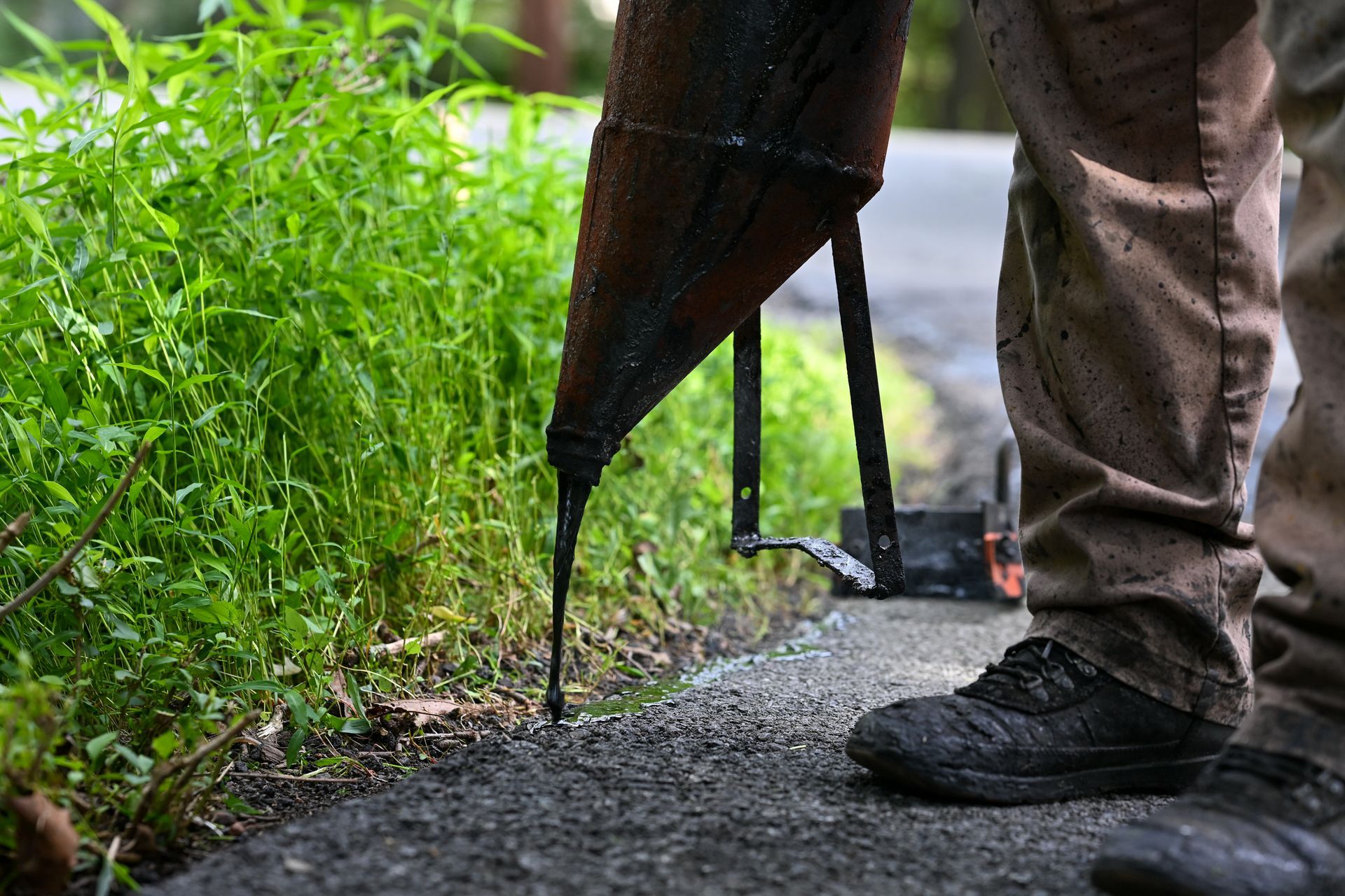 A person is pouring asphalt on the side of a road.