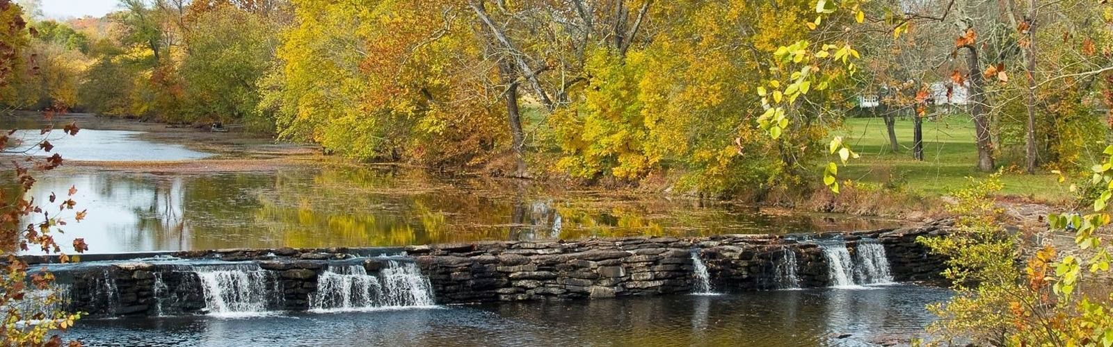 There is a waterfall in the middle of a river surrounded by trees.