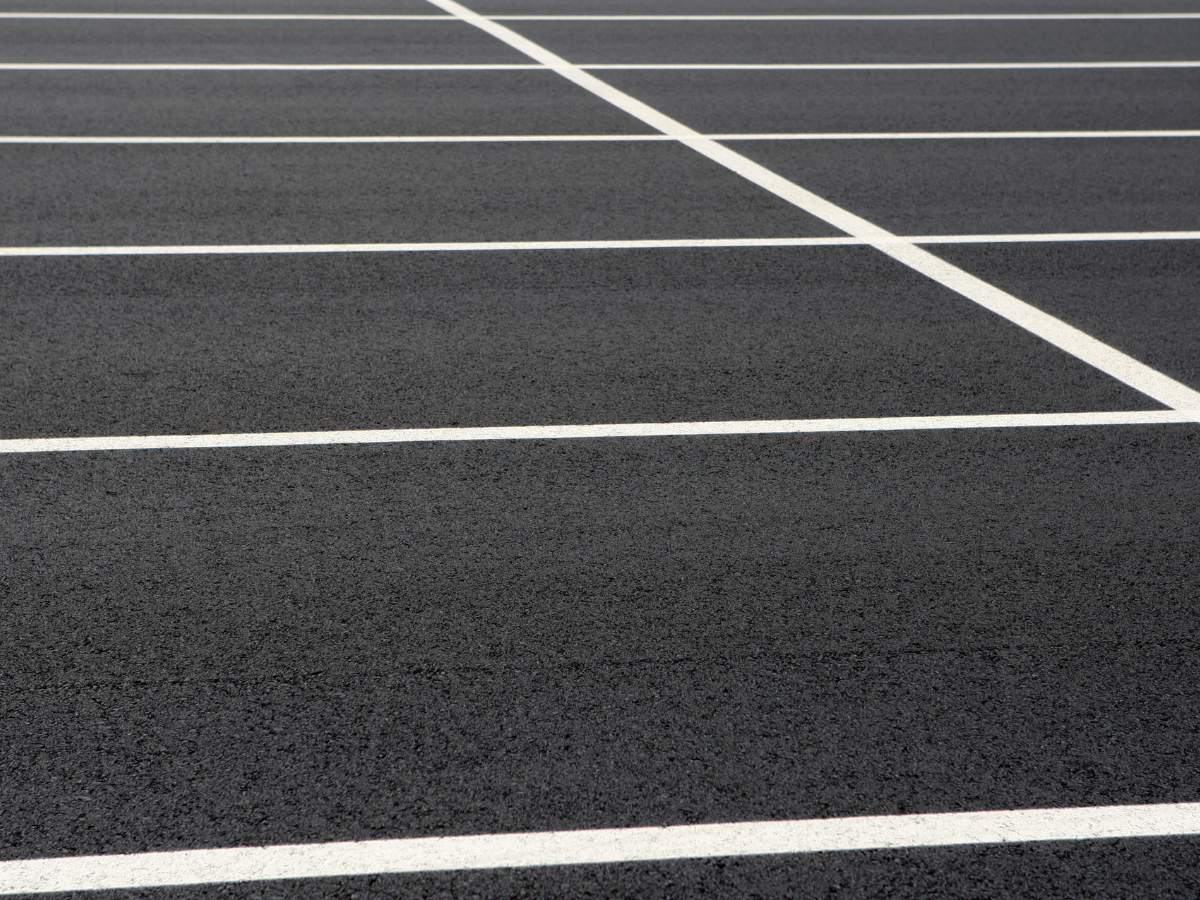 A close up of a parking lot with white lines on it.