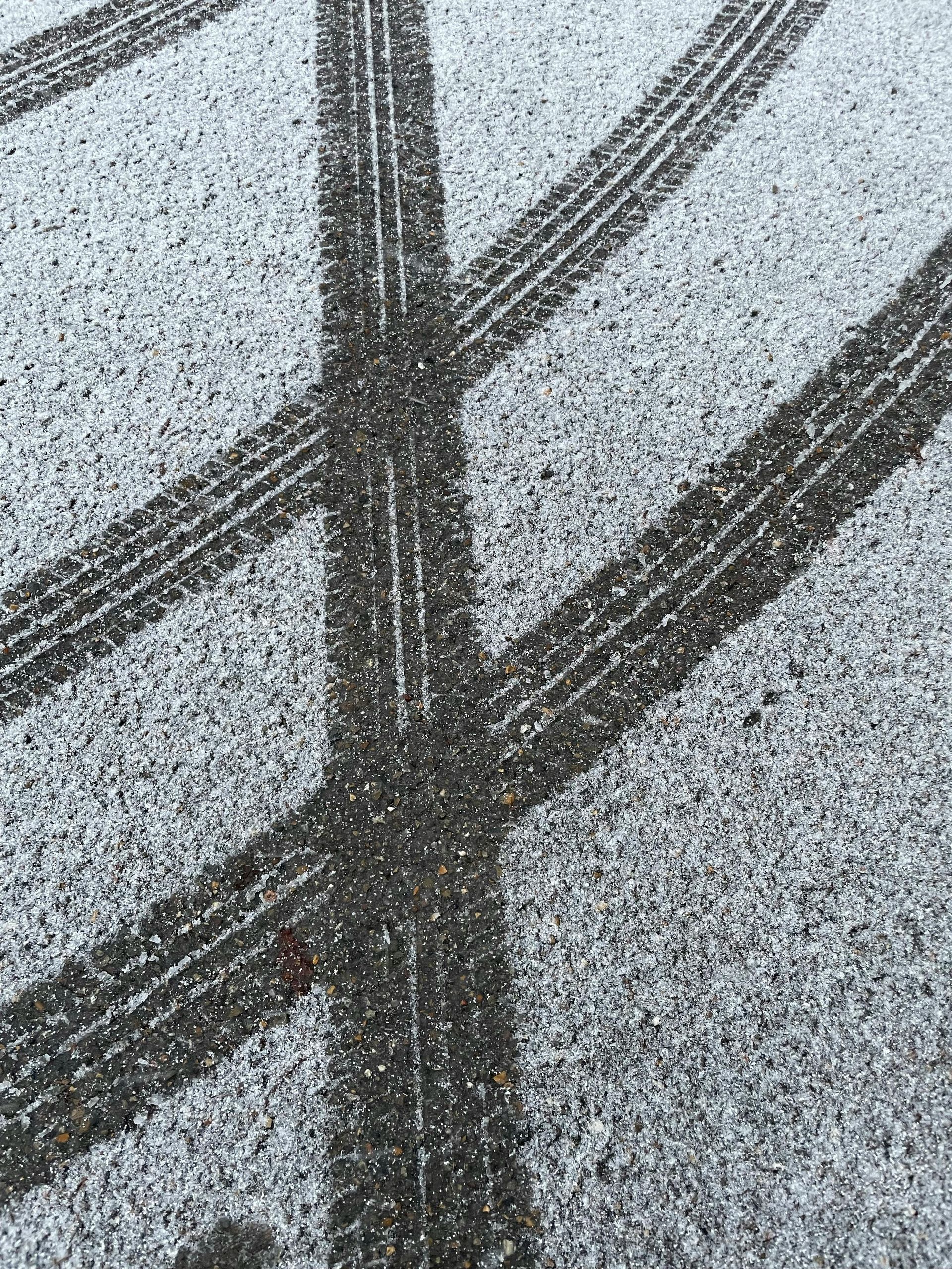 A close up of tire tracks on a snowy road.