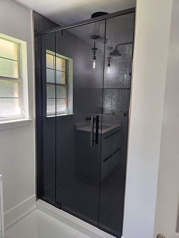 A bathroom with a black shower door and a window.