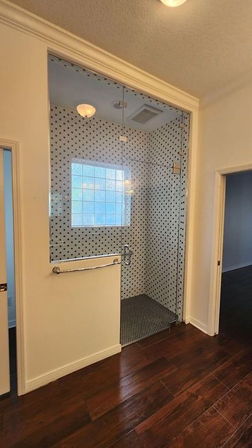 A bathroom with a walk in shower and a window.