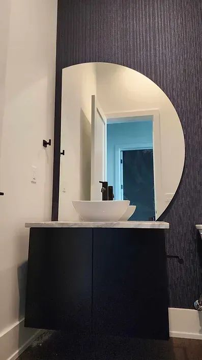 A bathroom with a sink and a round mirror.