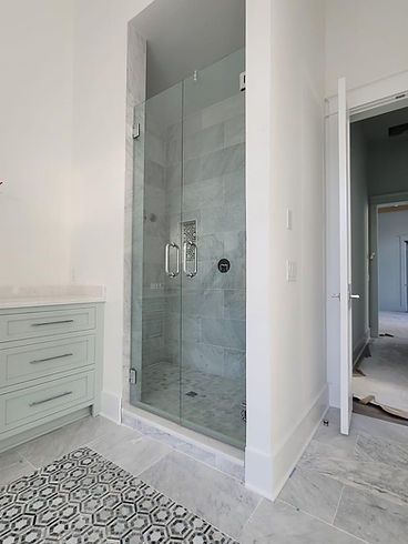 A bathroom with a walk in shower with a glass door.