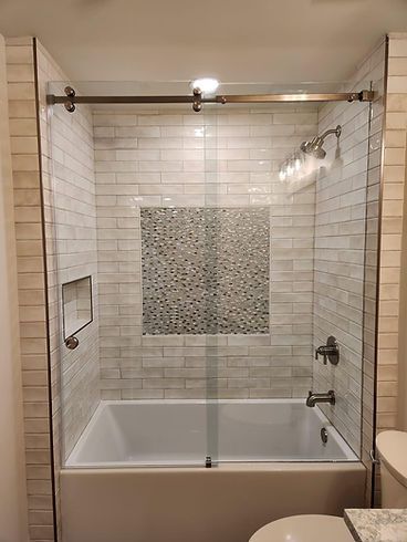 There is a bathtub in the shower with a glass door.