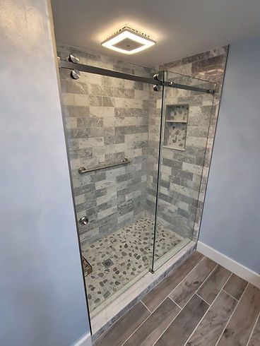 A bathroom with a walk in shower with a sliding glass door.
