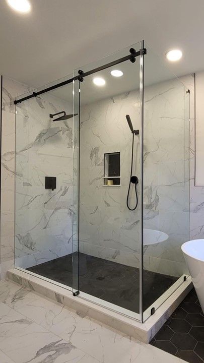 A bathroom with a walk in shower with sliding glass doors.