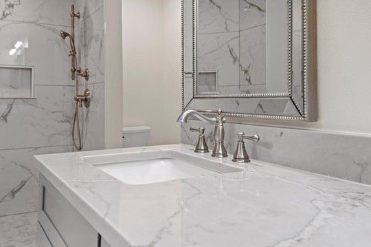 A bathroom with a sink , mirror and shower.