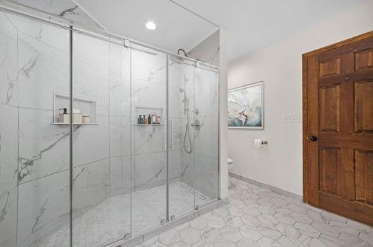 A bathroom with a walk in shower with sliding glass doors.
