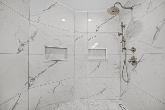 A shower with marble tiles and a shower head.