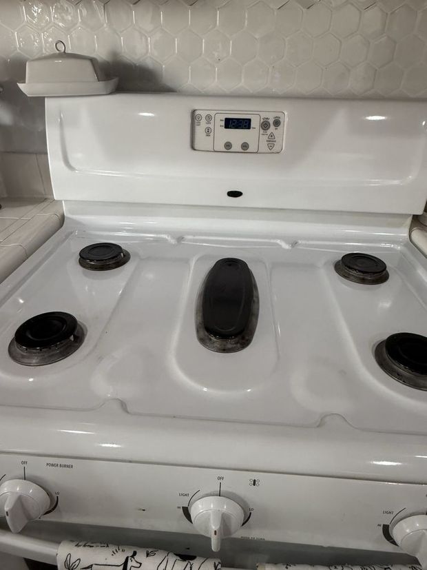 White electric stove with four burners and control knobs in a kitchen.