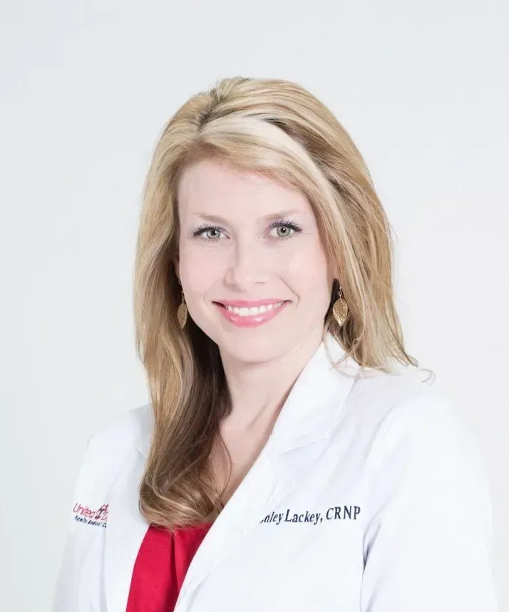 A woman in a white lab coat is smiling for the camera