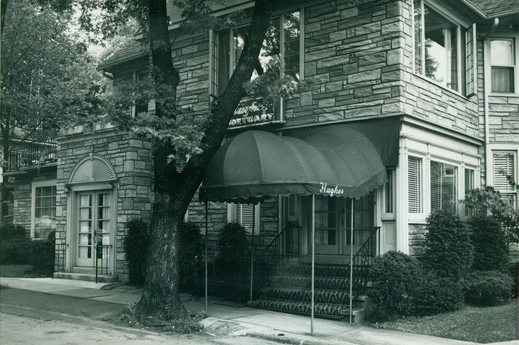 A black and white photo of a brick building with a green awning