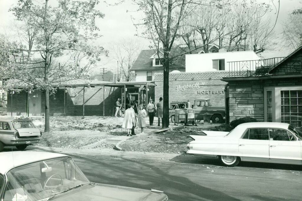 A black and white photo of a car parked in front of a building