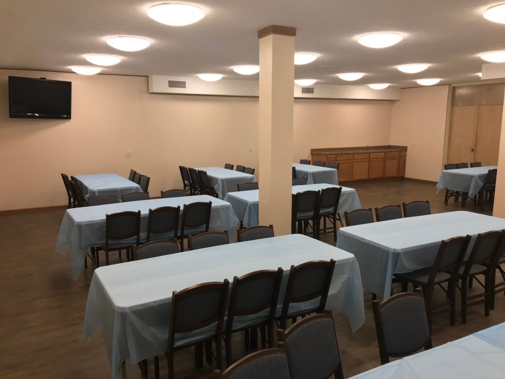 A large room with tables and chairs and a tv on the wall