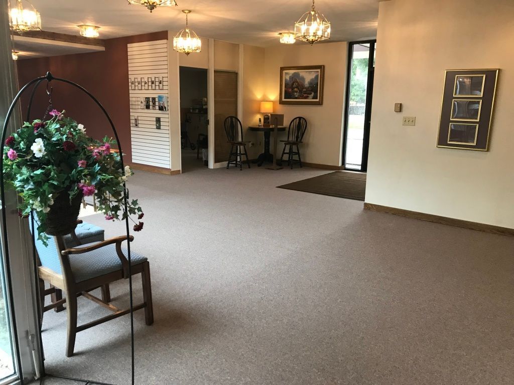 A large room with a chair and a vase of flowers.