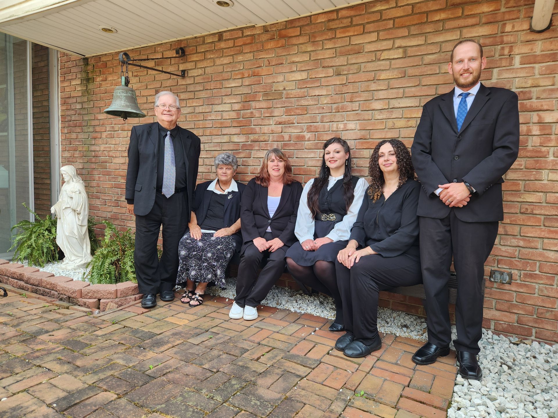 A group of people standing next to each other in front of a brick wall.