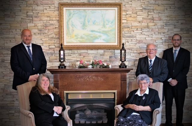 A group of people standing next to each other in front of a brick wall.