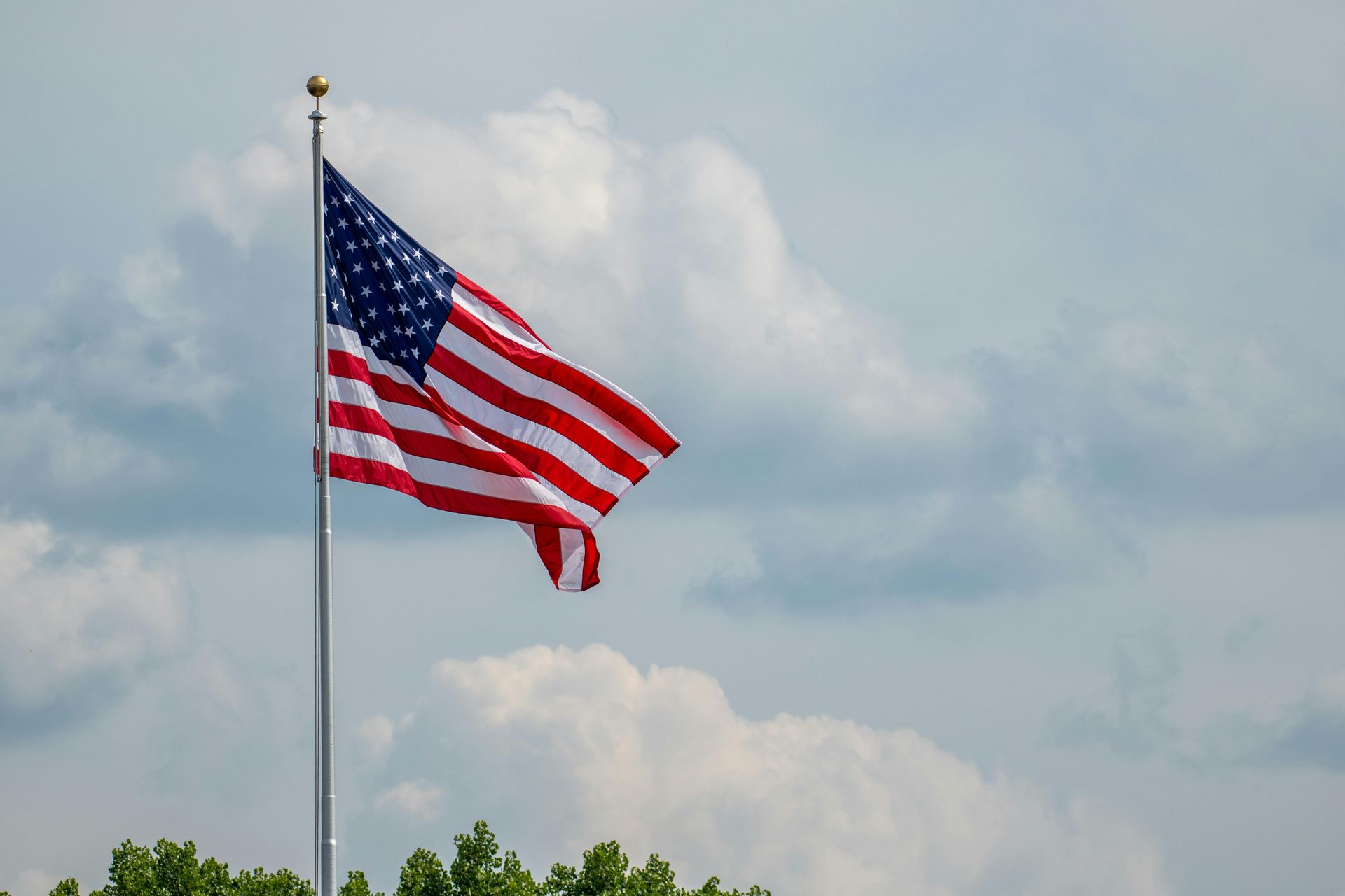 The american flag is waving in the wind on a cloudy day.
