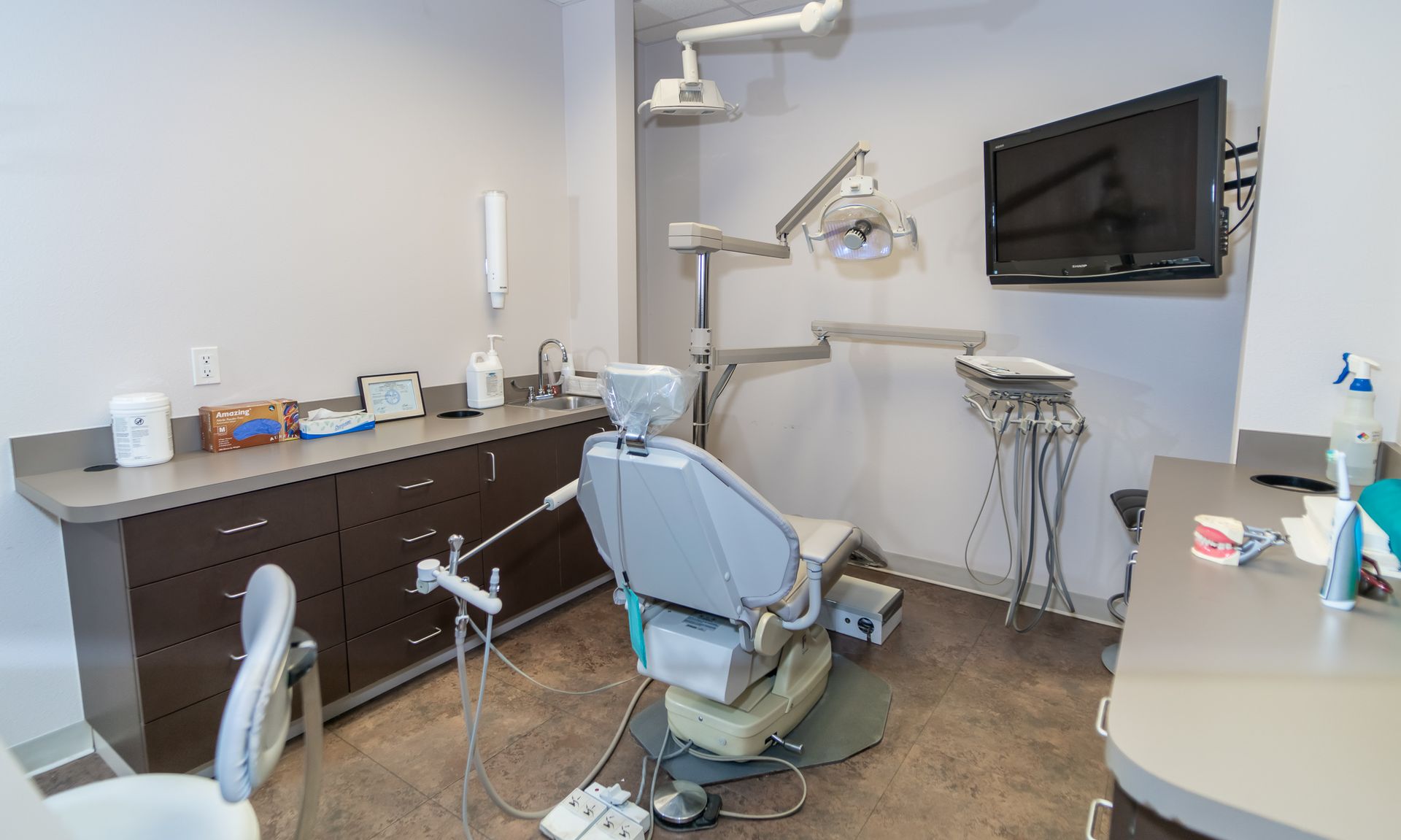 A dental office with a dental chair and a television on the wall.
