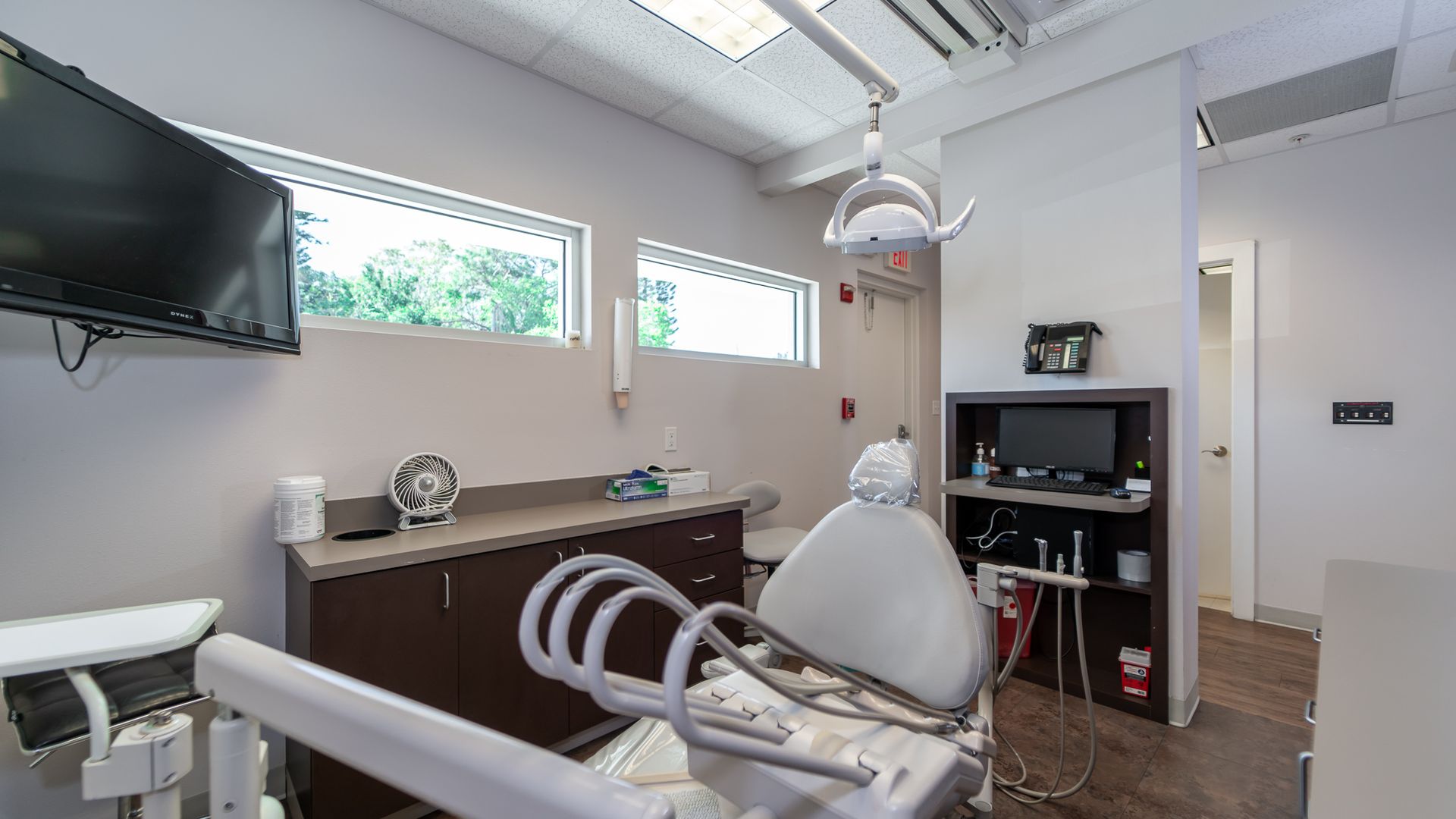A dental office with a dental chair and a television on the wall.