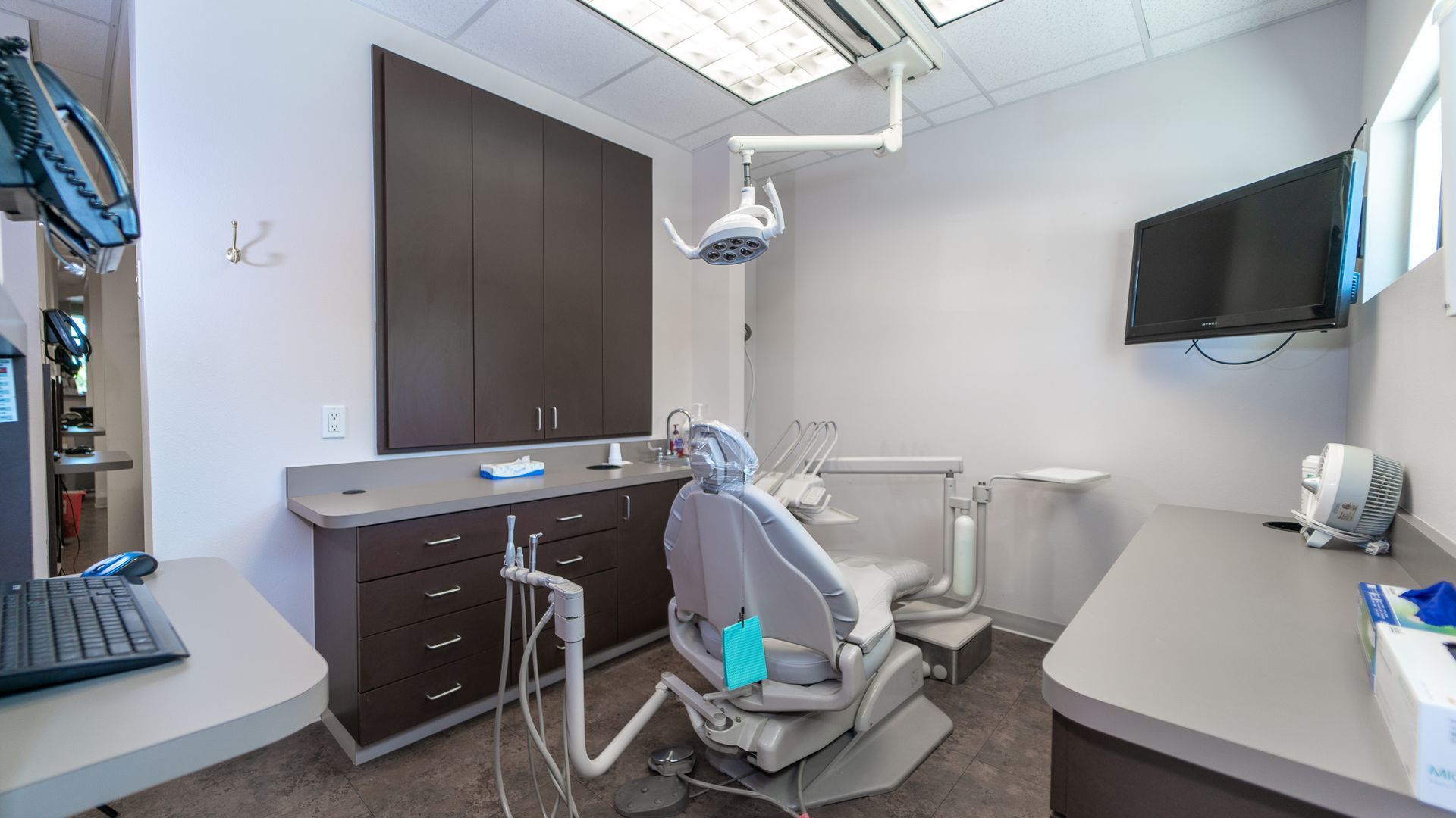 A dental office with a dental chair and a desk.