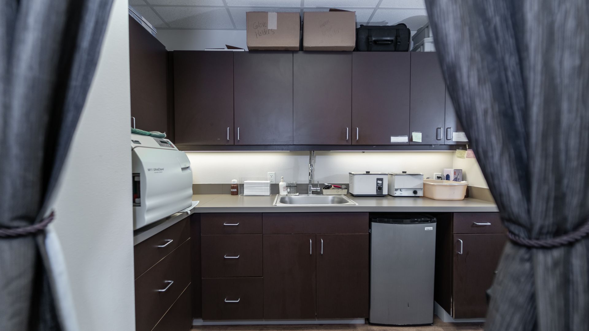 A kitchen with brown cabinets , a sink , and a refrigerator.